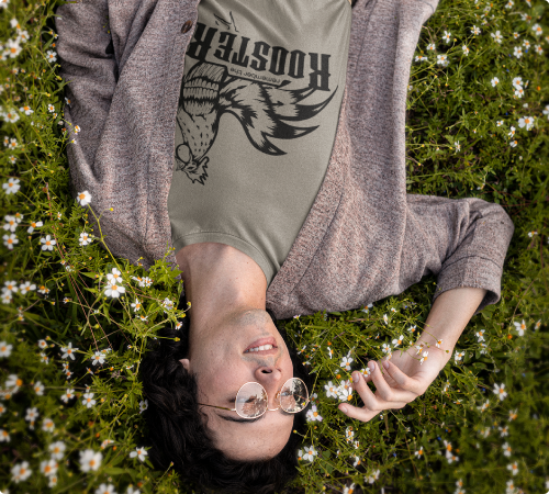 Man with glasses laying in a flower field with a christian t shirt of a rooster